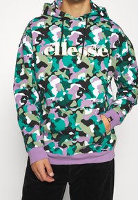 Sudadera con capucha de camuflaje en verde, púrpura, negro y blanco; cuenta con un bolsillo delantero, capucha con cordón y el logo dorado "ellesse". Fabricada en mezcla de algodón.