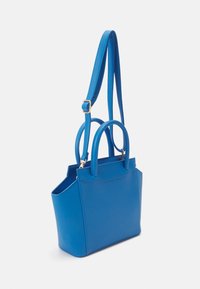 Sac à main en cuir bleu avec deux poignées et une bandoulière réglable. Présente une forme structurée et une texture lisse. Design minimaliste.