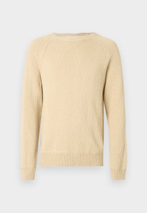 Lyst beige teksturert genser med rund hals og lange ermer. Har ribbestrikkede mansjetter og kant. Vovet mønster synlig over hele.