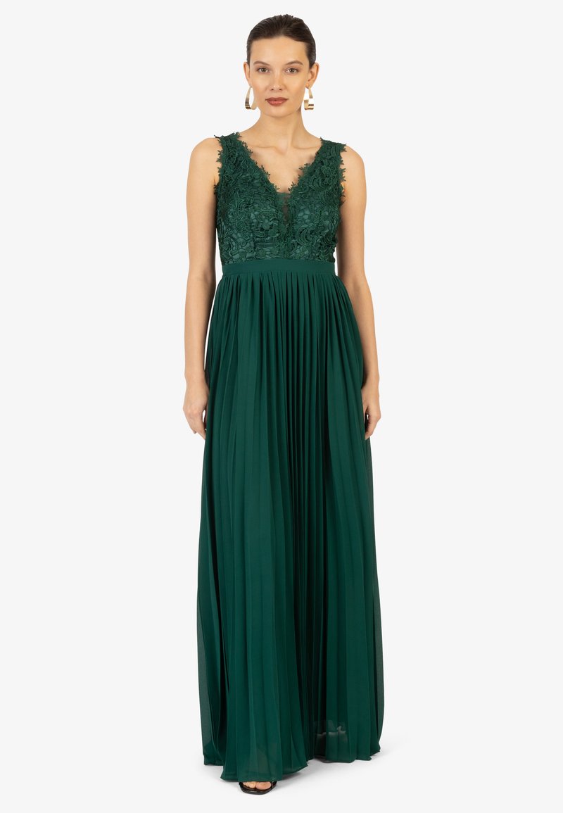 Langes smaragdgrünes Kleid mit tiefem V-Ausschnitt, besticktem Oberteil und plissiertem Rock. Glatter Stoff mit fließender Silhouette.