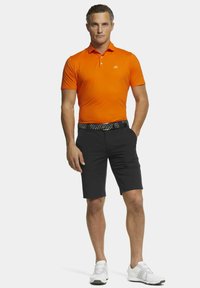 Oranje poloshirt, zwarte shorts, kleurrijke patroonriem en witte sportieve schoenen. Casual sportkleding met een slim fit ontwerp.