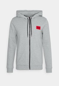 Felpa grigia con zip in misto cotone, con una cerniera nera, cappuccio regolabile con coulisse e una patch rossa con logo sul petto.