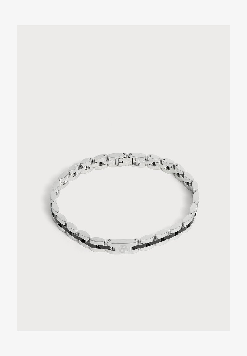 Bracelet chaîne en métal ton argenté avec des maillons ovales et un fermoir rectangulaire décoré d'un motif gravé, présenté sur fond blanc.