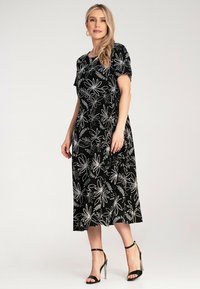 Black velvet dress with white floral pattern, short sleeves, and a mid-calf length. Paired with black high-heeled sandals.