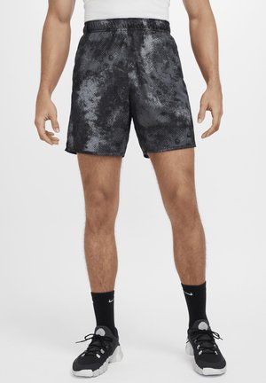 Shorts de sport noirs avec un motif abstrait gris, taille élastique et poches latérales, associés à des baskets et des chaussettes noires.