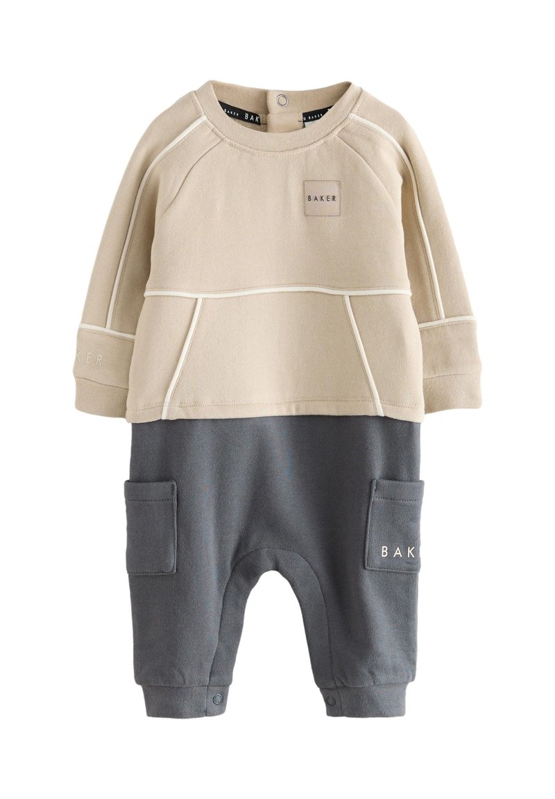 Beige top med raglanærmer og et rektangulært mærke med teksten "BAKER"; kombineret med grå bukser med sidelommer og trykknapslukning.