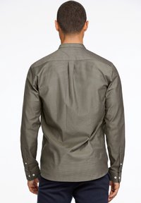 Olijfgroene lange mouwen blouse met een rugnaad, knoopmanchetten en een gestructureerde stof. Heeft een klassieke kraag en een rechte zoom.