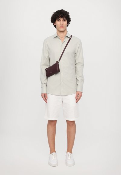 Cămașă butonată de culoare verde deschis, pantaloni scurți albi și adidași albi. Geantă de umăr de un burgund închis. Design simplu cu textură netedă.