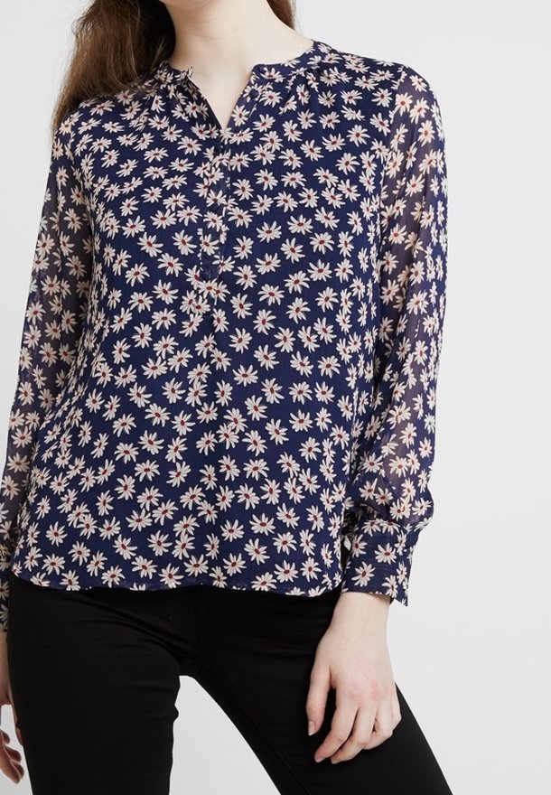 Marinblus med långa ärmar, prydd med ett blommönster av rosa och vita prästkragar. Tillverkad av lätt, semi-genomskinligt material.