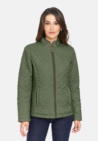 Chaqueta acolchada verde oliva con cuello alto, cierre frontal de cremallera y bolsillos laterales. Presenta un intrincado patrón tejido y herrajes en contraste.