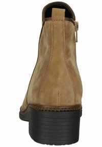 Bottine en daim marron avec un bout rond et un talon en caoutchouc noir. Elle présente des coutures minimales et une fermeture éclair à l'arrière pour un enfilage facile.