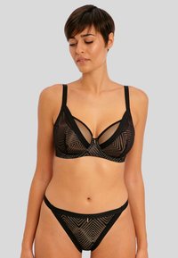 Soutien-gorge noir et thong assorti arborant un motif géométrique avec des panneaux transparents. Les bretelles sont ajustables avec une texture lisse et un design épuré.
