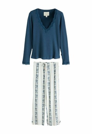 Long-sleeve ribbed blue top with lace trim paired with white wide-leg pants featuring vertical blue floral stripes and a drawstring waist.