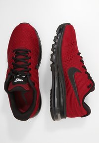 Červené tenisky Nike s prodyšným síťovinovým svrškem, černými akcenty a polstrovanou černou podrážkou s viditelnou vzduchovou jednotkou.