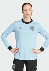 Light blue long-sleeve soccer jersey with black accents. Features ribbed texture and embroidered logo on the chest, paired with black shorts.