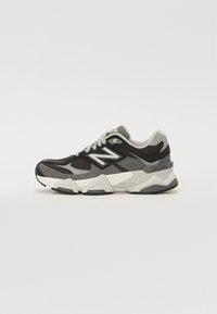 Scarpe sportive con una combinazione di colori nero, grigio e bianco. Presentano materiali in mesh e suede, una suola intermedia spessa e un marchio prominente sul lato.