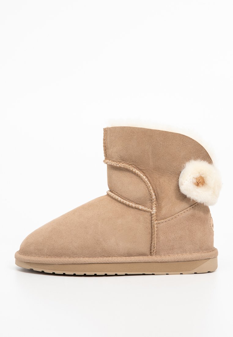 Beżowe zamszowe botki za kostkę z miękkim, białym futerkiem wewnątrz i dekoracyjnym pomponem z boku. Płaska gumowa podeszwa.
