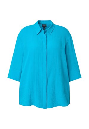 Kirkkaan sininen, löysä naisten paita, jossa on kolme neljänneksen hihaa, terävä kaulus ja edessä piilotettu napitus.