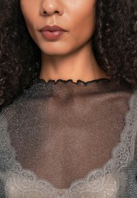 Kerge must topp, millel on sakilise kaeluse ja pitsakad, esitades kena kergelt särava tekstuuri, mis paljastab selle all oleva heleda aluse.