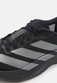 Czarny but biegowy Adidas z szarymi paskami, czarnymi sznurówkami, metką "ADIZERO" i szczegółem podeszwy "LIGHTSTRIKE PRO", widok z boku pod kątem.