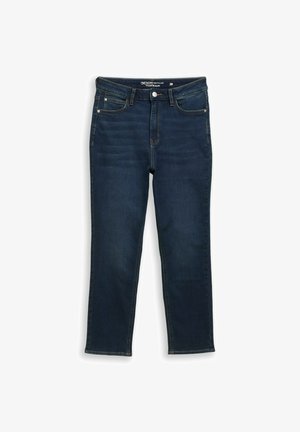 Tumši zilas pieguļošas džinsus ar priekšējo pogu, kabatām un maziem nolietojuma akcentiem, izklātus uz baltas fona.