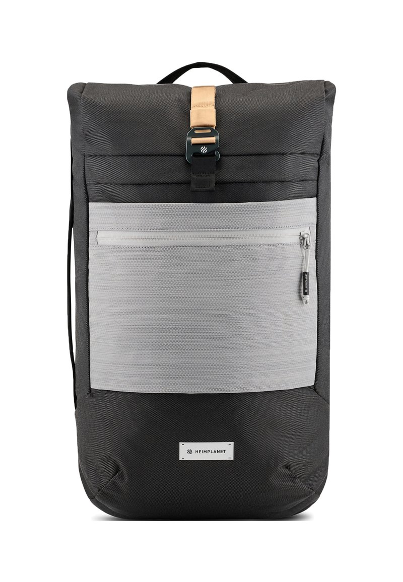 Zaino realizzato in tessuto nero con tasca frontale grigia a texture. Presenta una tracolla beige e una chiusura in metallo. Include spallacci regolabili.