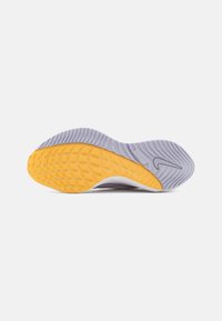 Semelle de chaussure avec une bande de roulement en caoutchouc texturé gris et jaune, présentant un design incurvé et un logo Nike swoosh près du talon.