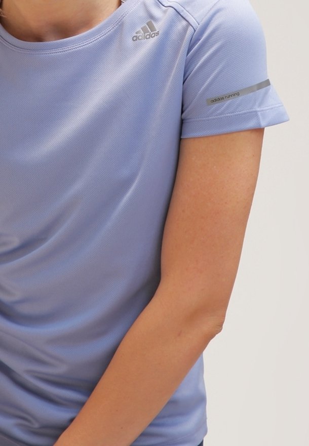 Gros plan d'une personne portant un maillot de course Adidas violet clair avec le logo sur la poitrine et le texte « adidas running » sur la manche.