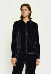 Must musta shirt kaelusega, pikal varrukal ja nööbiga ees. Pehme tekstuur, õmmeldud sobivus ja poleeritud viimistlus.