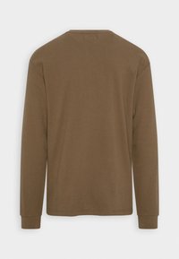 Pitkähihainen ruskea T-paita, valmistettu pehmeästä kankaasta, jossa on pyöreä pääntie ja mansetit hihoissa. Ei näkyviä kuvioita tai metalliosia.