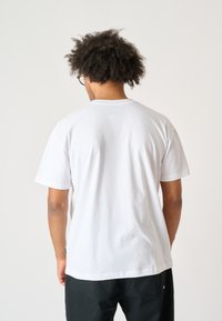 White cotton T-shirt with a classic crew neck and short sleeves. Simple, solid color with no visible patterns or graphics.