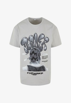 Světlé šedé bavlněné tričko s grafickým designem, na kterém je slovo "SÍLA" tučným, stylizovaným černým písmem a ilustrací postavy zezadu.