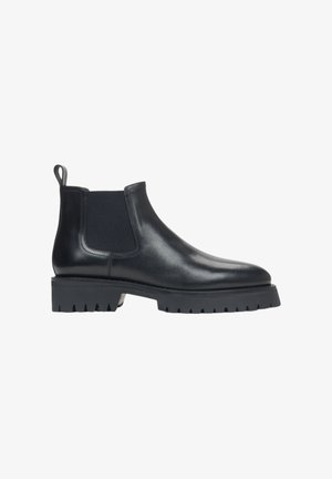 Black leather Chelsea boots with elastic side panels, rounded toe, and thick rubber sole featuring a jagged edge for traction.