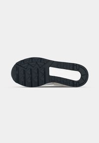 Black rubber shoe sole with deep treads and a zigzag pattern. Features a white midsole and 'Saucony' branding near the heel.