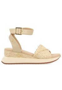 Las sandalias de cuña beige presentan un upper trenzado, una correa para el tobillo con hebilla dorada y una suela texturizada. El diseño combina materiales naturales y sintéticos.