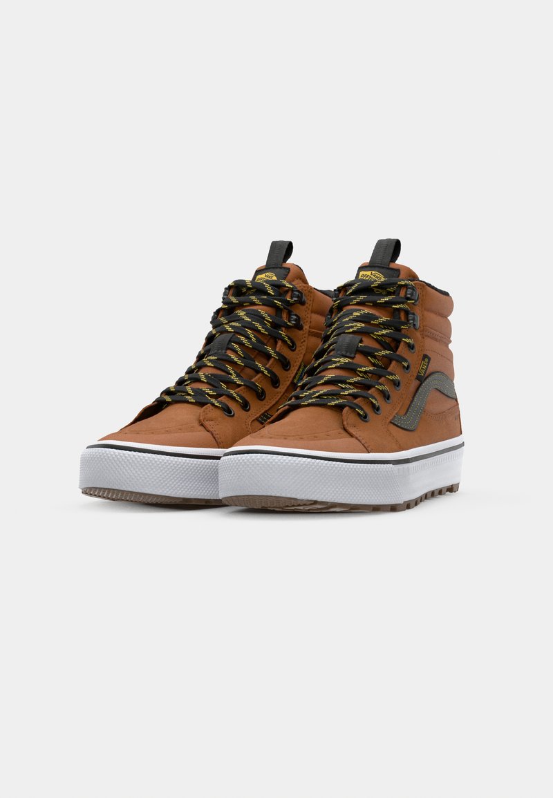 Zapatillas altas marrones con cordones negros y amarillos estampados, suela de goma blanca, parte superior de tela texturizada y acentos laterales grises.