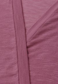 Detailní záběr složené růžové pleteniny ukazující žebrované okraje a hladkou strukturu.