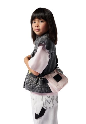 Denim vest met rafelige randen, versierd met zilveren studs. Lichtroze schoudertas met een zwarte patch, gecombineerd met witte broek met donkere accenten.