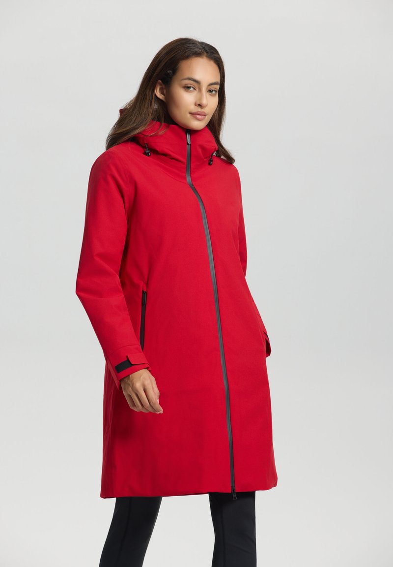Manteau long imperméable rouge avec un col haut, une fermeture éclair à l'avant et des poches latérales. Présente des accents noirs et des cordons de serrage ajustables sur la capuche.