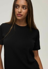 Czarny t-shirt z krótkim rękawem wykonany z bawełny, z okrągłym dekoltem i dopasowanym krojem, zapewniającym gładką sylwetkę.