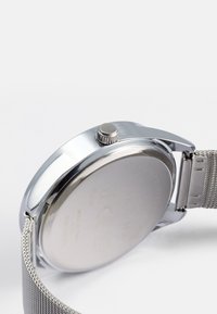 Orologio in acciaio inossidabile di colore argento con cinturino a rete, dotato di una cassa rotonda, corona sul lato e un retro liscio e lucido.