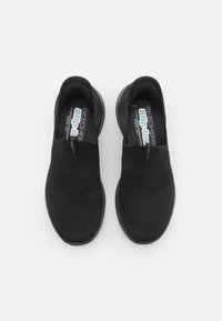 Svarta slip-on sneakers med en texturerad meshtopp, elastiska band för enkel påtagning och en vadderad sula för komfort.