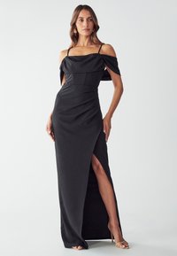 Abito da sera nero con scollo off-shoulder, tessuto arricciato, alta apertura sulla gamba sinistra e spalline sottili. Texture liscia con una silhouette aderente.