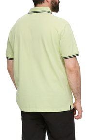 Jasnozielona koszulka polo z czarnymi paskami przy kołnierzyku i mankietach, wykonana z bawełny. Posiada prosty krój z bocznymi rozcięciami u dołu.