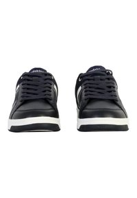 Zapatillas de cuero negro con suelas de goma blanca y cordones, que presentan detalles en gris en los laterales y un collar acolchado para mayor soporte.