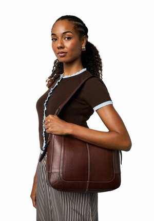 Brun skuldertaske af læder med en glat tekstur, hvide syninger og en bred rem. Tasken har en rektangulær form og minimalistisk detaljer.