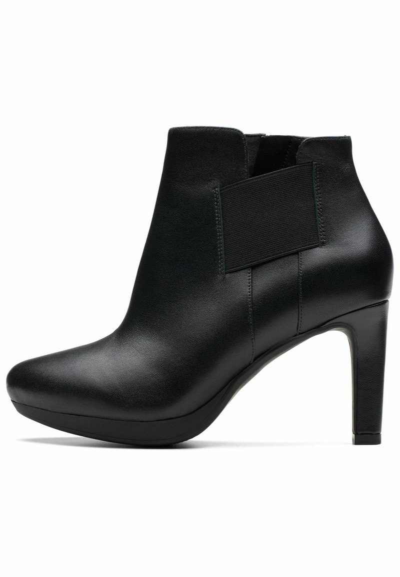 Bottine en cuir noir avec bout pointu, panneau latéral élastique et talon bloc haut sur fond blanc.