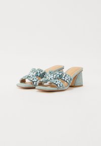 Lichtblauwe suède sandalen met blokhak, voorzien van een gekruiste band versierd met sprankelende edelstenen en een gladde, tan voetbed.
