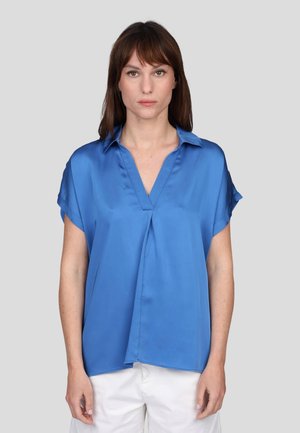Chemise en satin bleu à manches courtes avec un col en V, présentant une coupe décontractée et un discret pli à l'avant, sur un fond neutre.