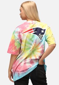 Pastellfärgad tie-dye T-shirt med rundad nederkant, som har en stor logotyp på baksidan av ett fotbollslag. Tillverkad i bomull, avslappnad passform.